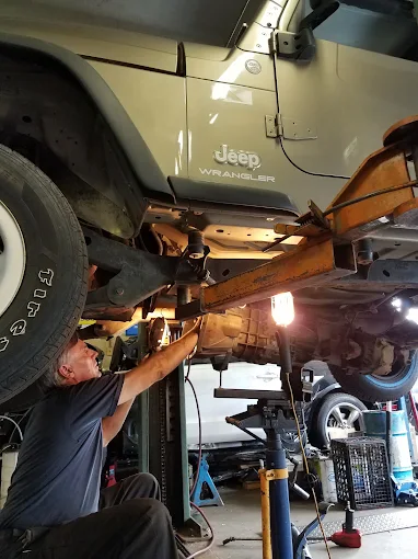 A Bieri Automotive mechanic working under a Jeep Wrangler on the lift