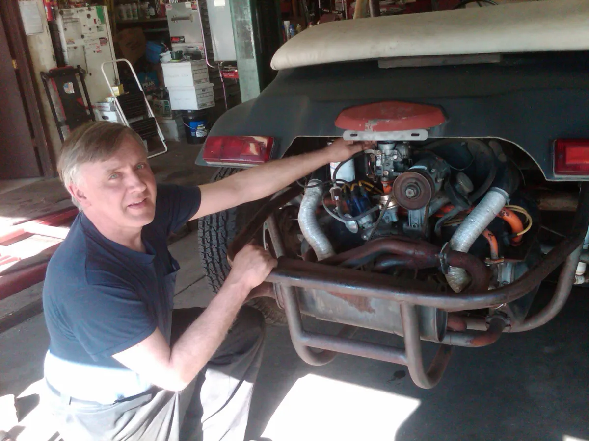 Ed working on the rear-mounted flat-four engine of a dune buggy with chrome header pipes