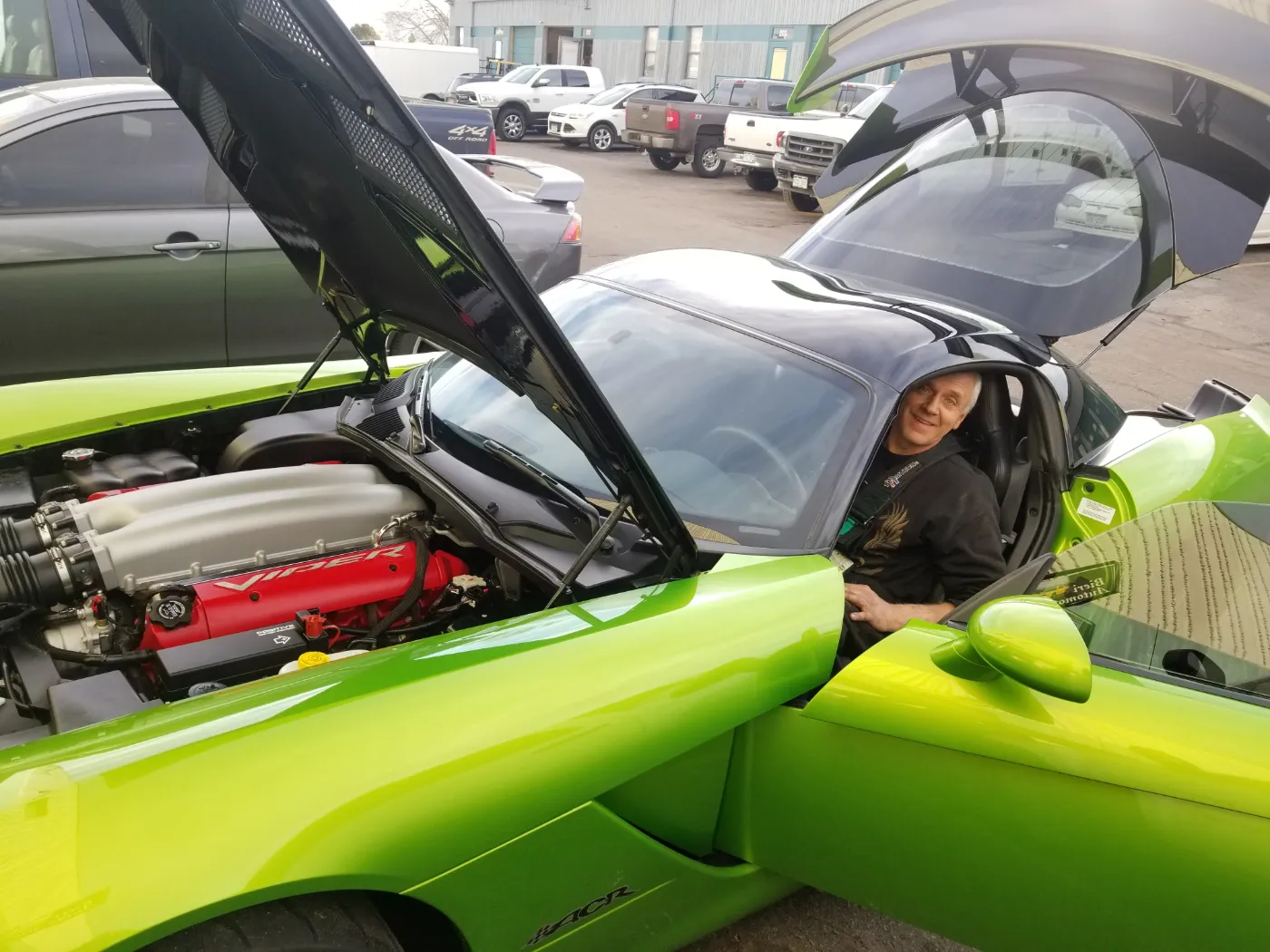 A green 2008 Viper ACR in the shop with its hood open and Ed in the driver’s seat